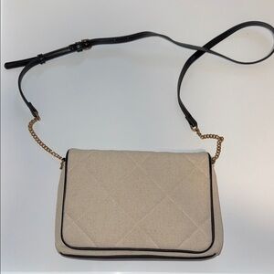 Beige quilted handbag w/ black piping and a black and gold chain crossbody strap